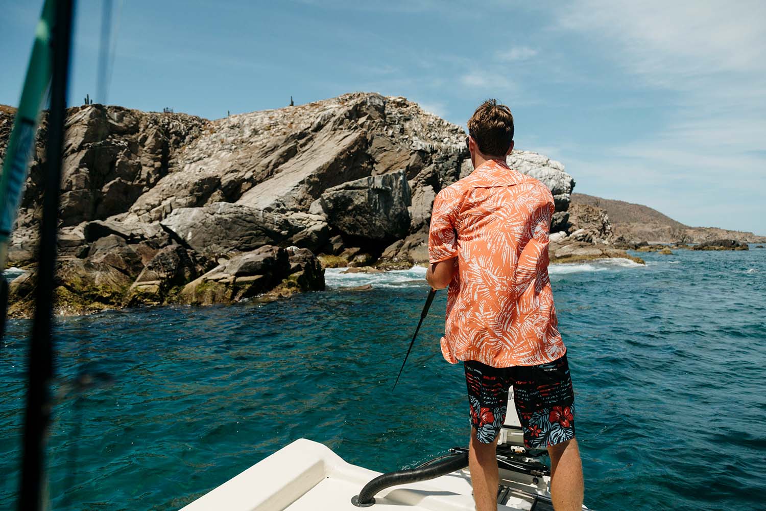 A man out in a small boat reel fishing while wearing Salty Crew Clothing.