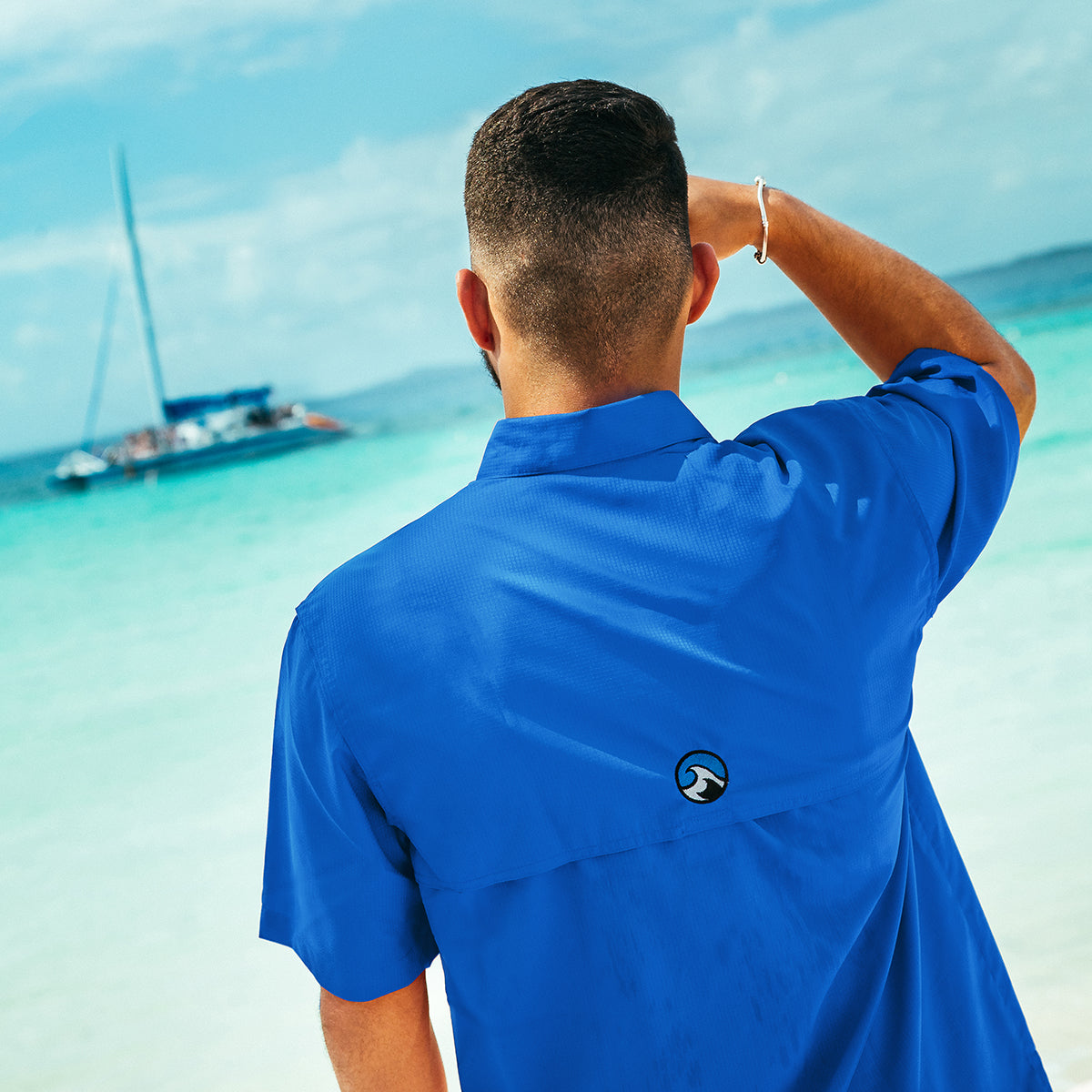 A Man stares at a boat out in the water while wearing a Costazul Tech Button Down Shirt