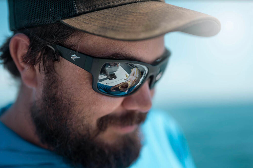 Fisherman wearing a Fin Noir sunglass while handling a fish.